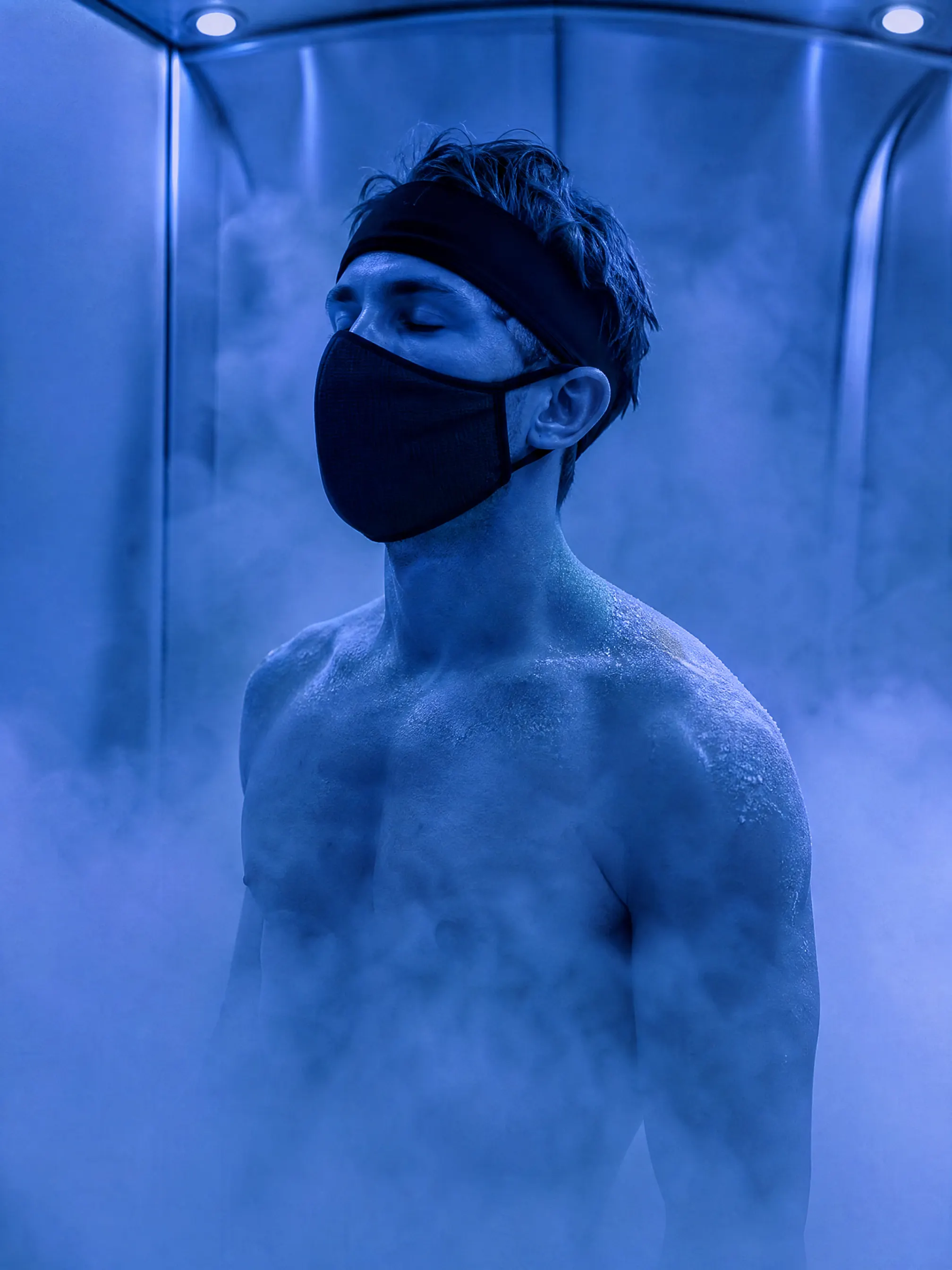 Guest standing inside a cryotherapy chamber surrounded by cold vapour